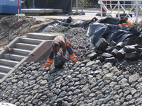 901607 Afbeelding van een werkman die met de hand basaltblokken aan het leggen is voor de nieuwe beschoeiing van het ...